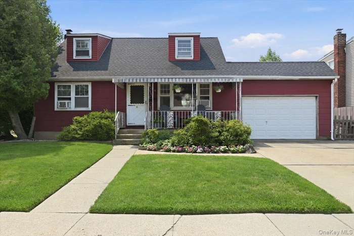 Red-sided residence featuring a covered front porch, white dormer windows, and a single-car garage with a white door
