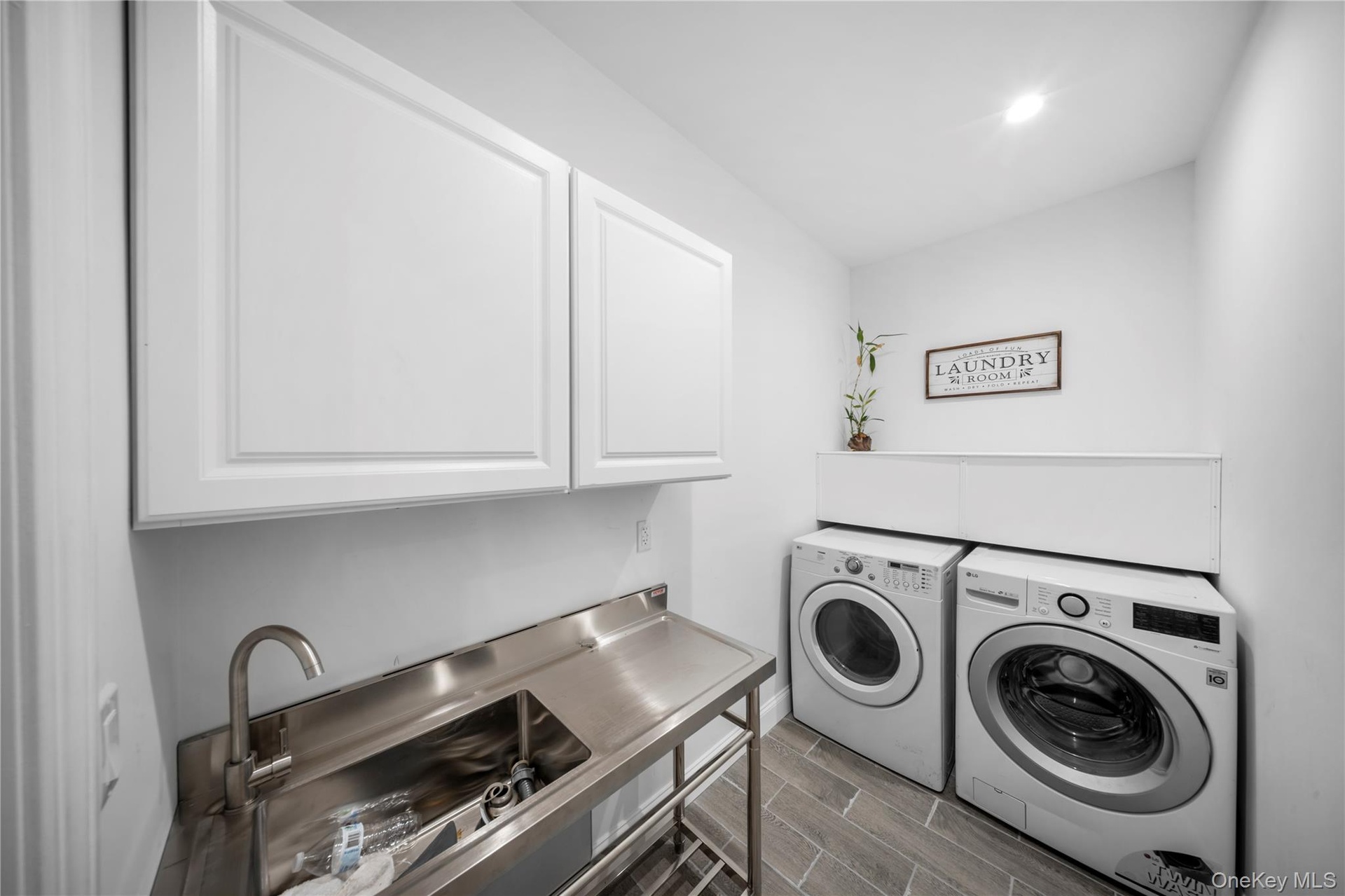 Laundry room featuring wood finish floors, washer and clothes dryer, cabinet space, and recessed lighting