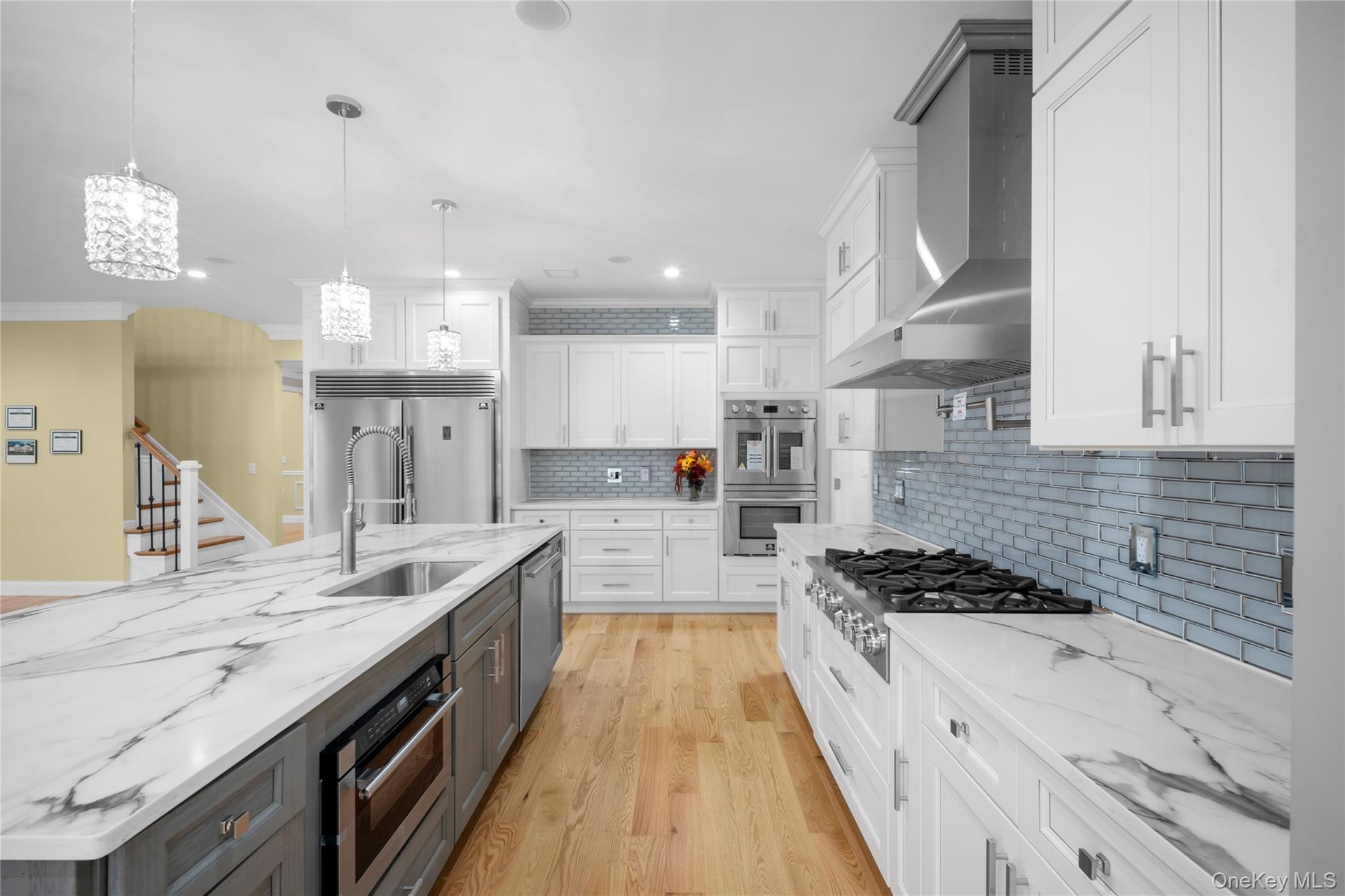Kitchen featuring white cabinets, light stone countertops, light wood-style flooring, wall chimney exhaust hood, and recessed lighting