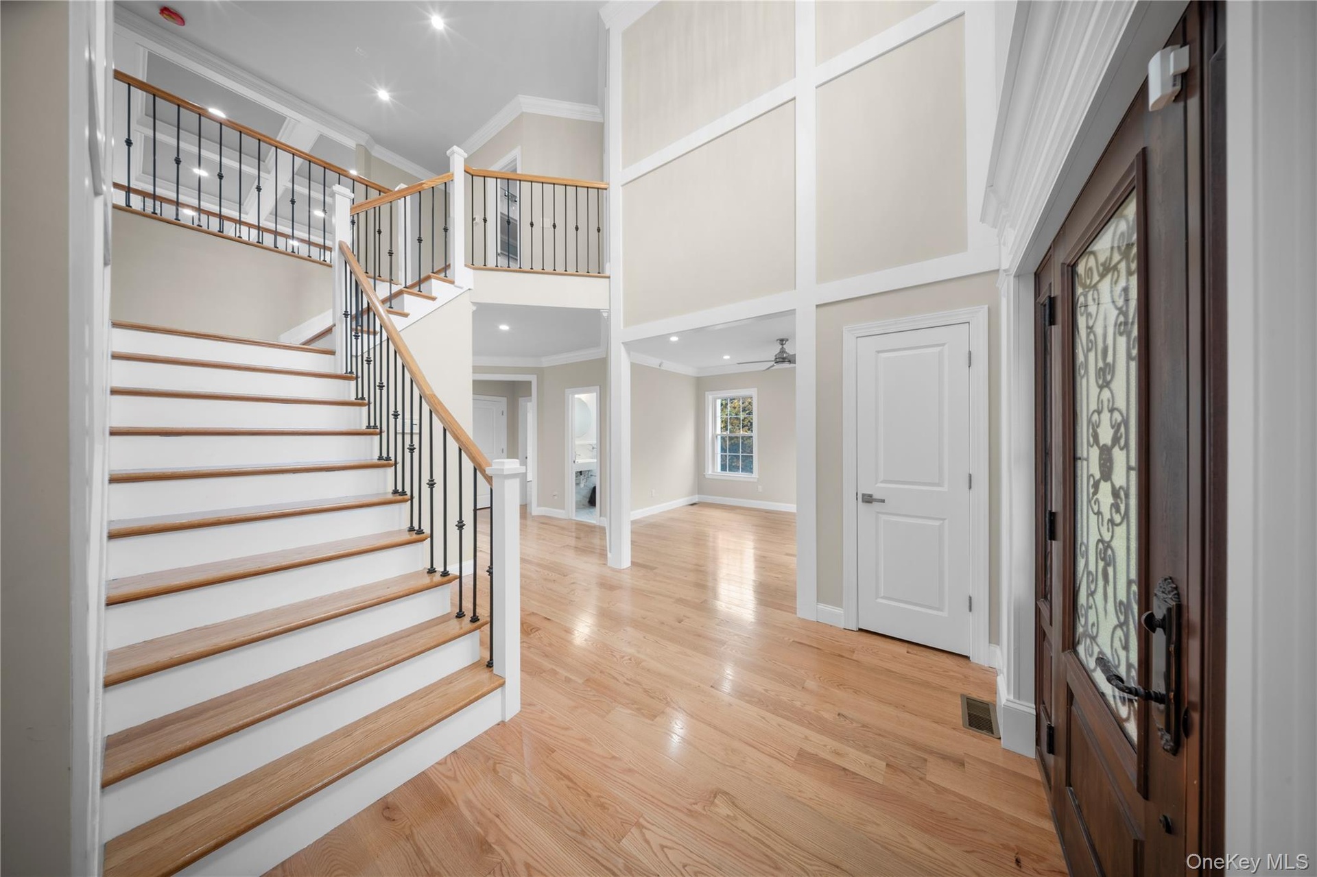 Entrance foyer featuring crown molding, a towering ceiling, a fireplace, light wood-style floors, and recessed lighting