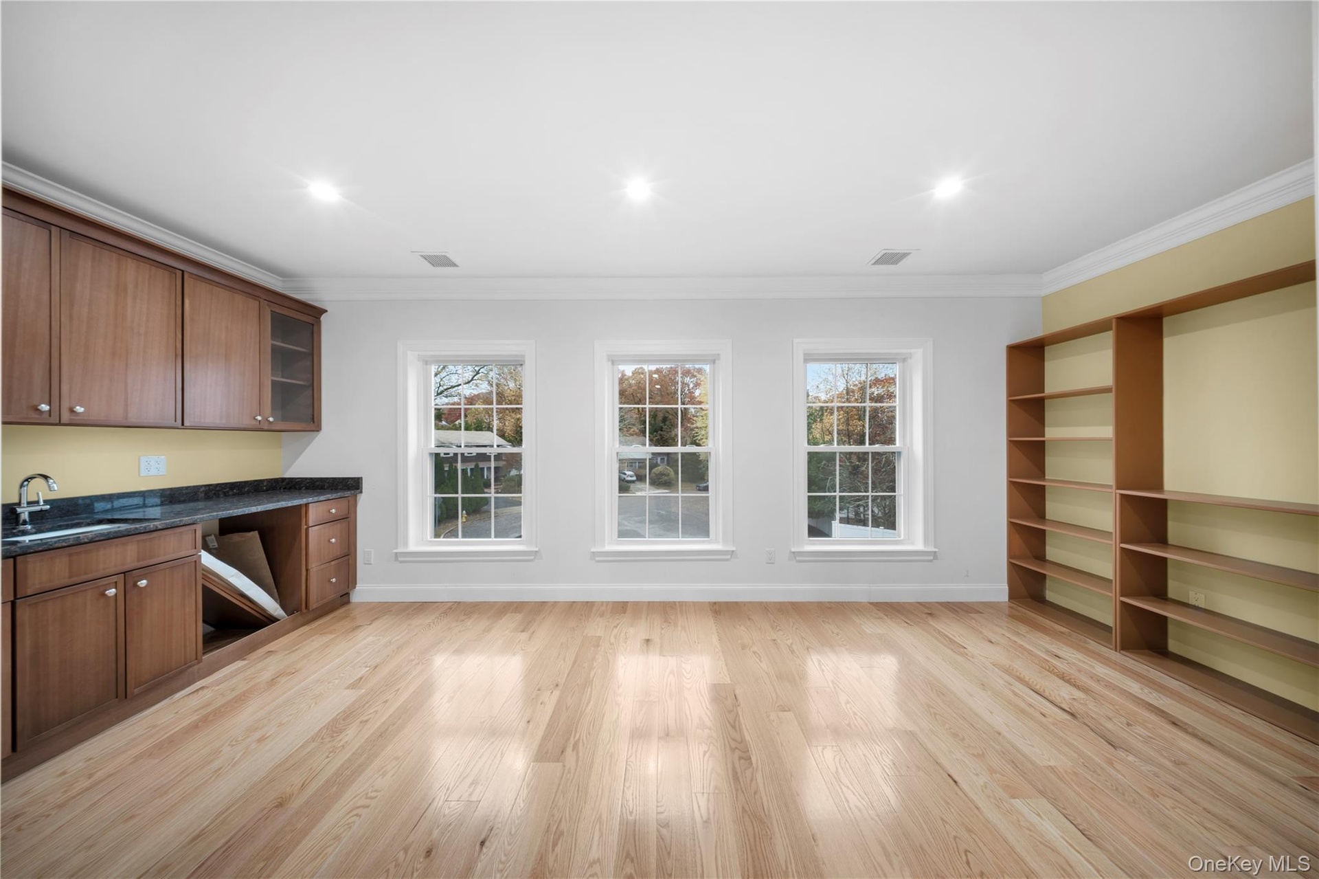 Bar area with crown molding, glass insert cabinets, light wood-type flooring, recessed lighting, and dark stone counters