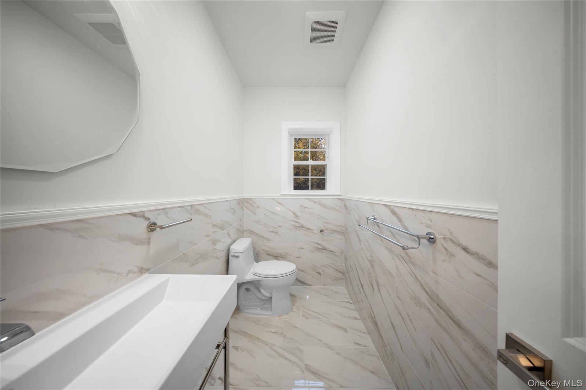 Bathroom with tile walls, a wainscoted wall, vanity, and marble finish flooring