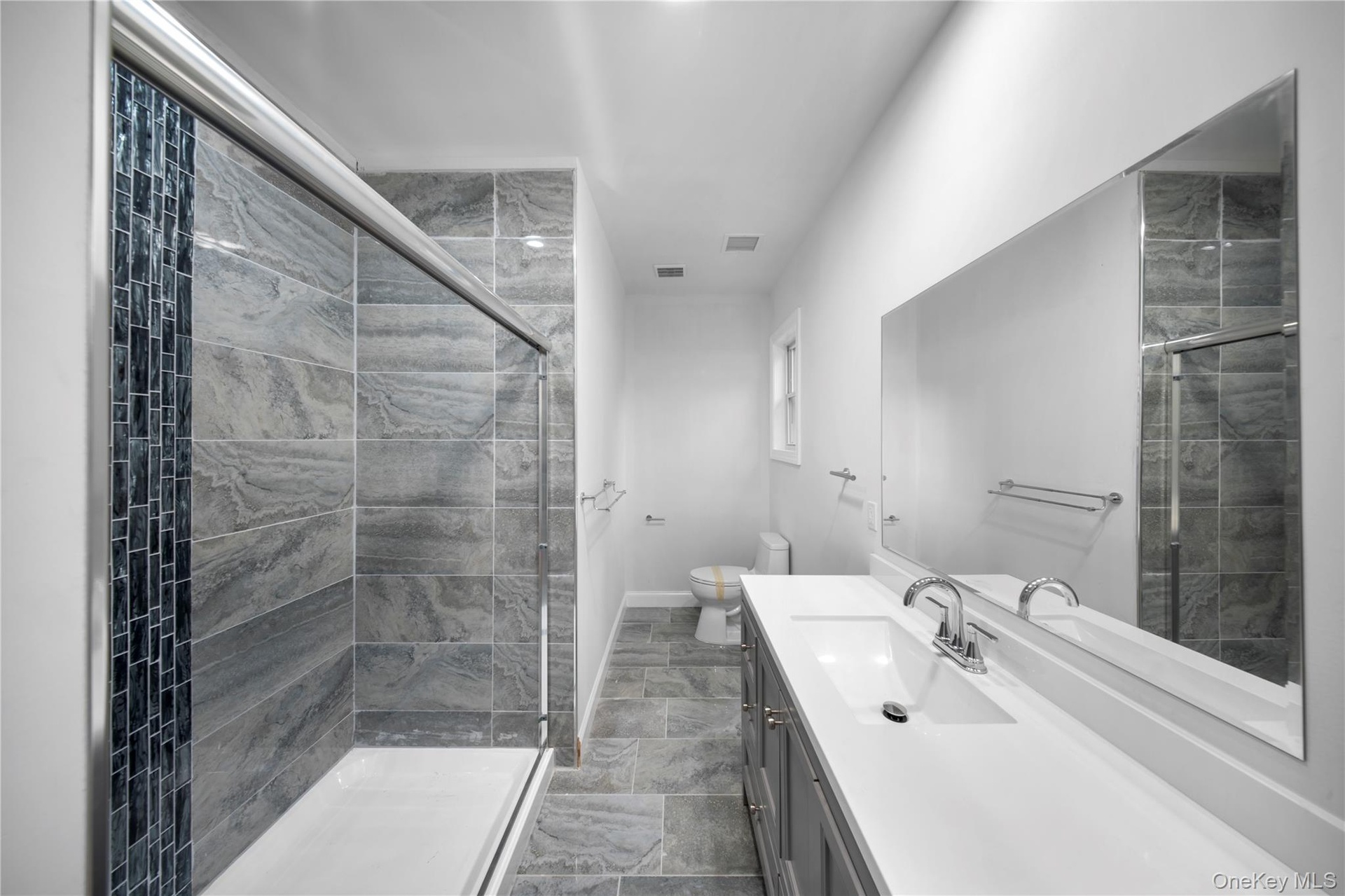Full bathroom with vanity, a stall shower, and dark stone finish flooring