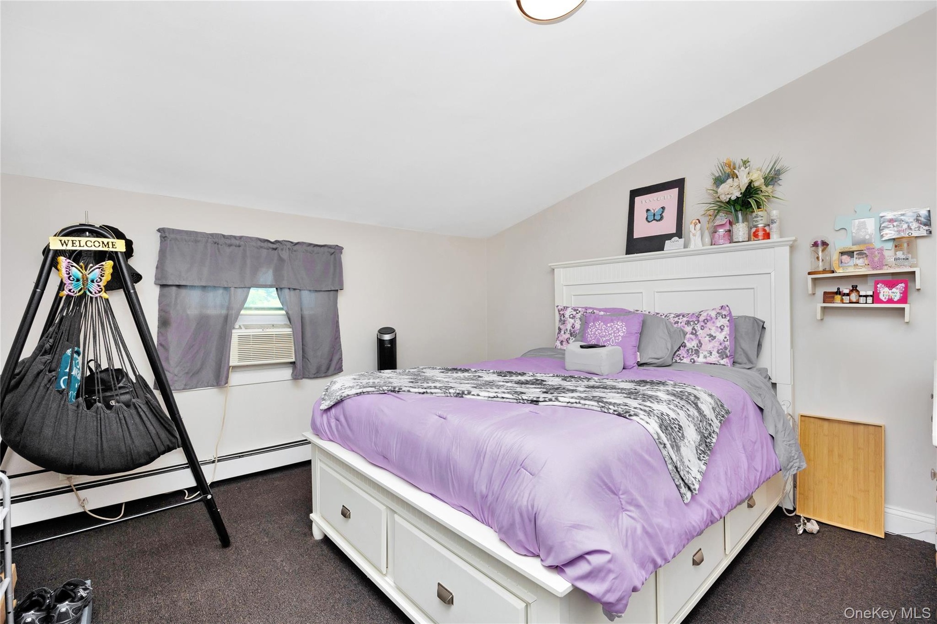 Bedroom with vaulted ceiling, dark carpet, cooling unit, and a baseboard radiator