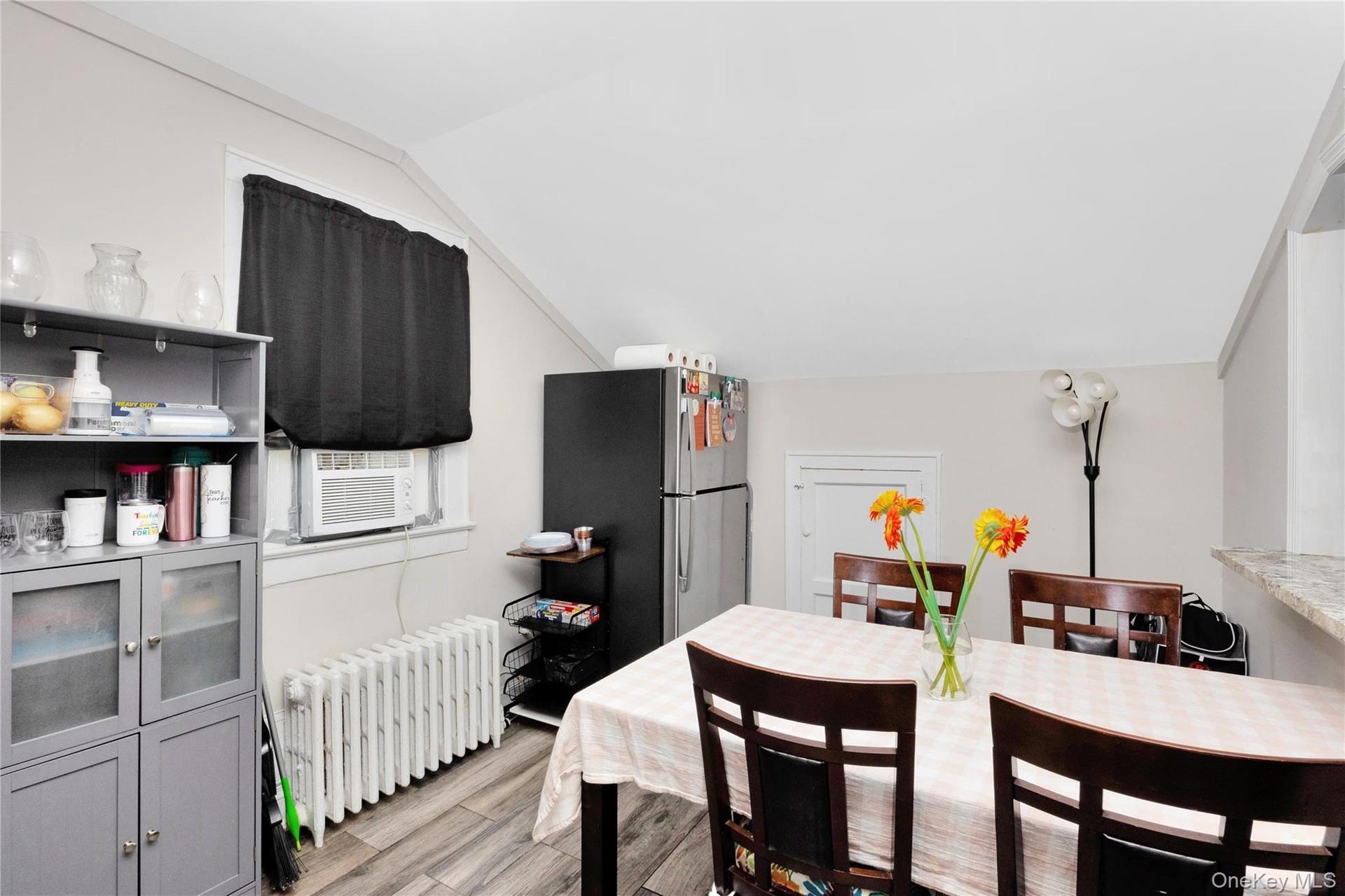 Dining room with radiator, light wood-style flooring, and lofted ceiling