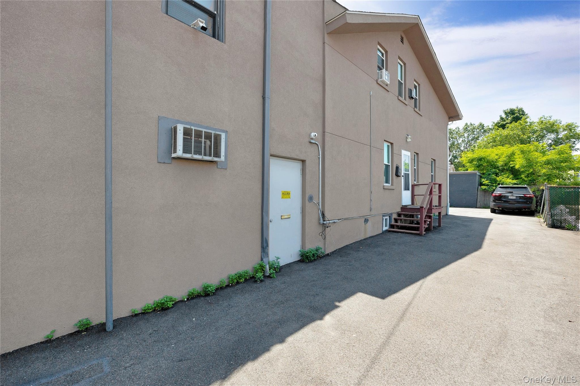 View of side of home with stucco siding and an AC wall unit