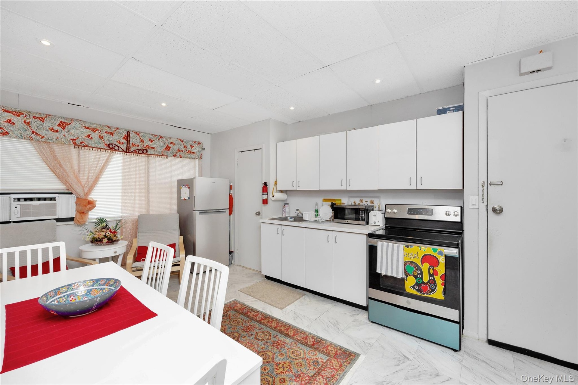 Kitchen featuring stainless steel appliances, a drop ceiling, white cabinets, light countertops, and cooling unit