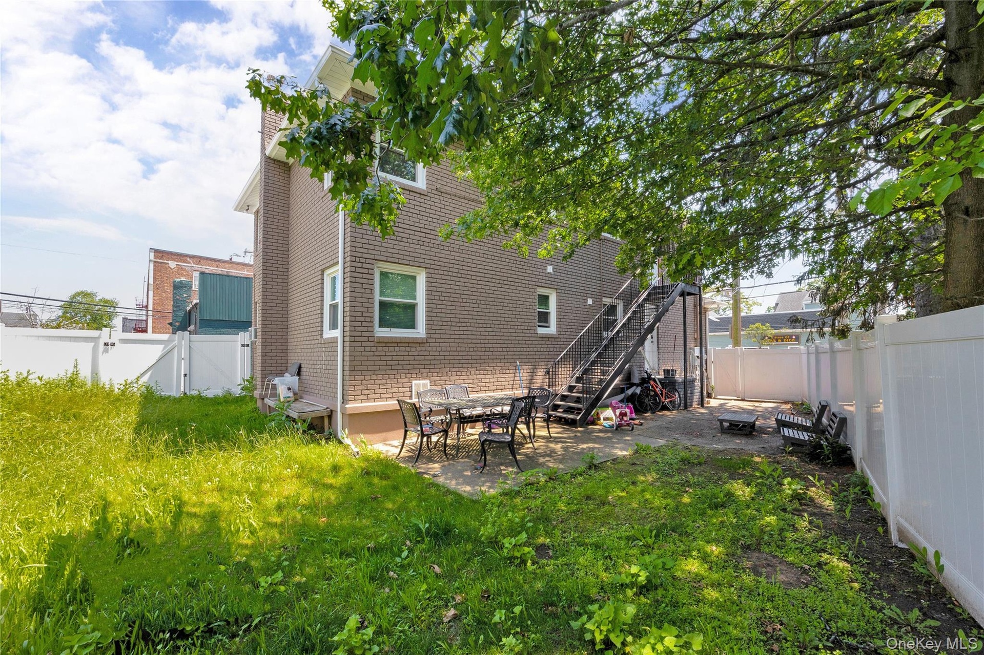 Back of property with a fenced backyard, a patio, and stairway