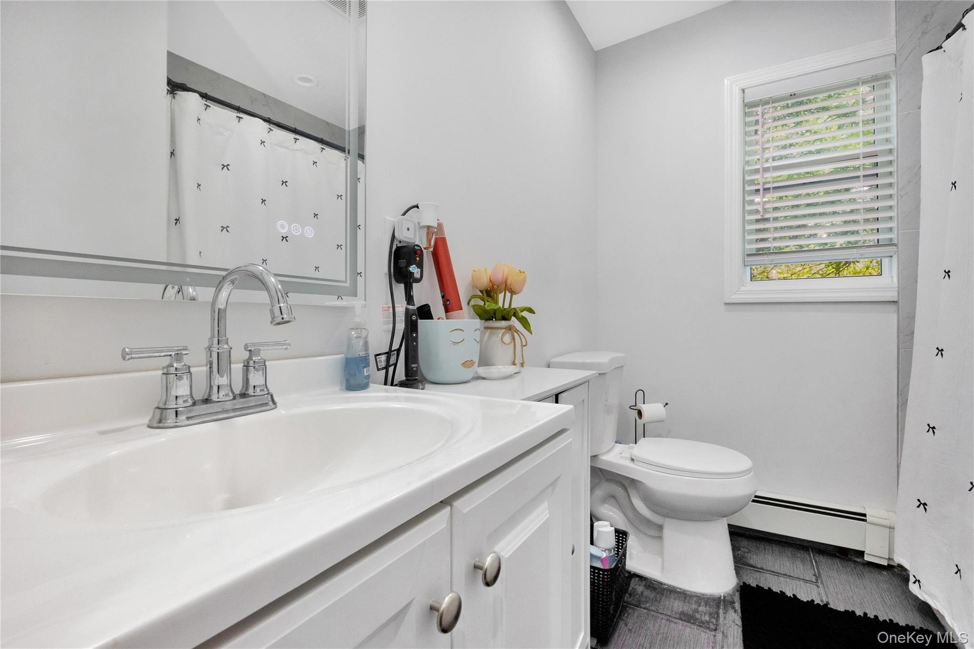 Full bath with a baseboard heating unit, vanity, and tile patterned floors