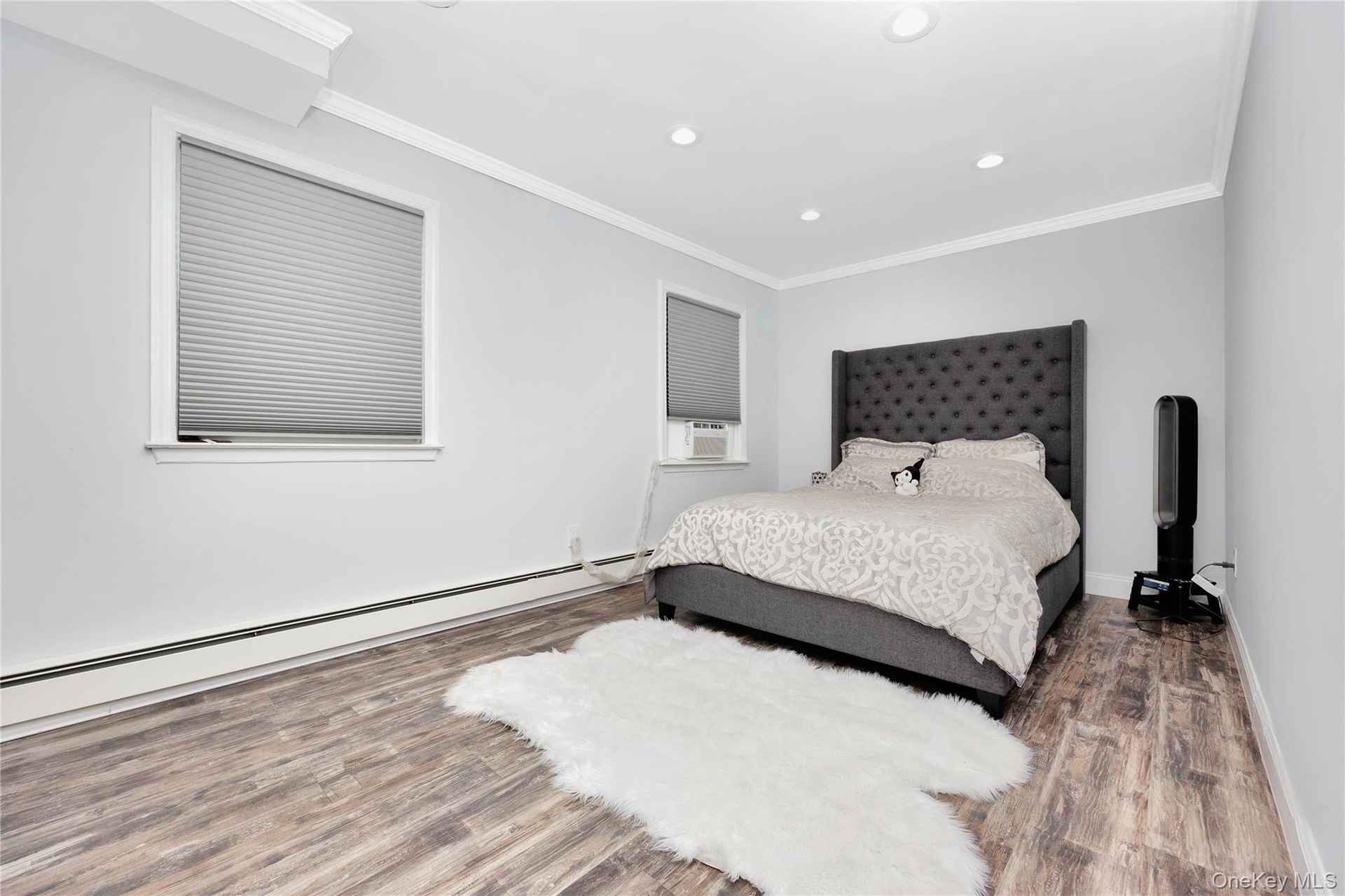 Bedroom with a baseboard heating unit, wood finished floors, recessed lighting, and crown molding
