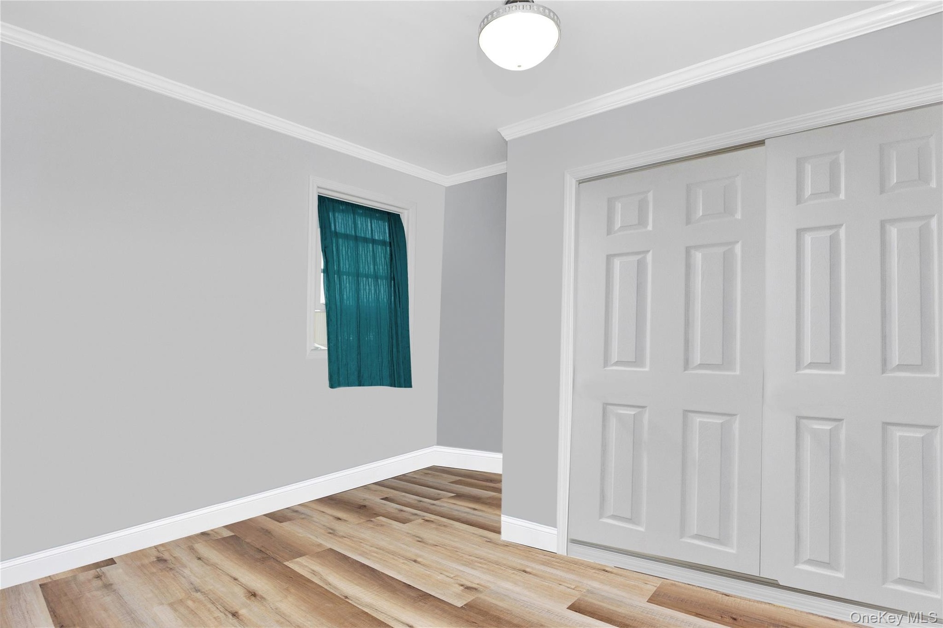 Unfurnished bedroom featuring light wood-style flooring, ornamental molding, and a closet