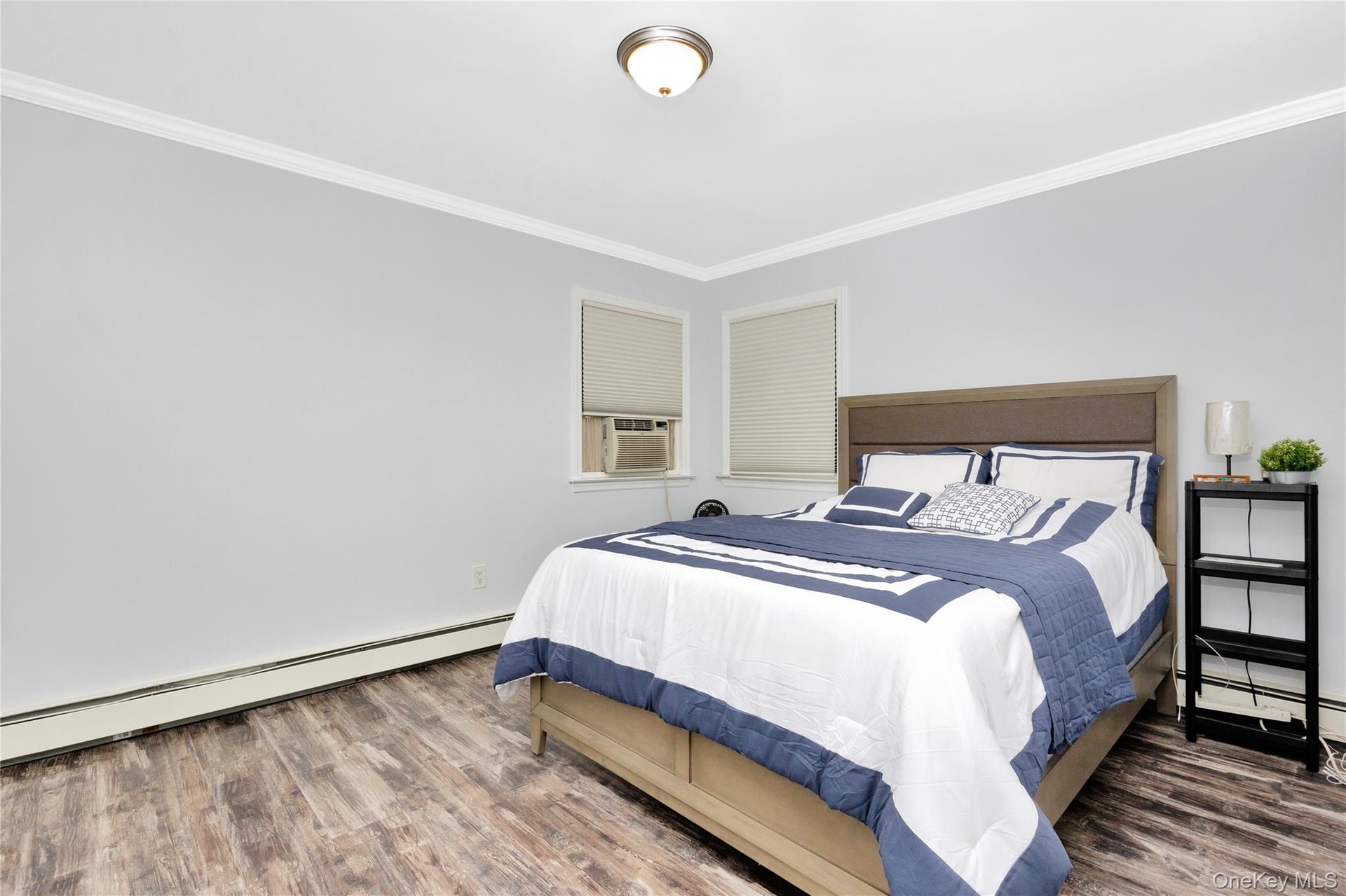 Bedroom featuring ornamental molding, a baseboard heating unit, wood finished floors, and cooling unit