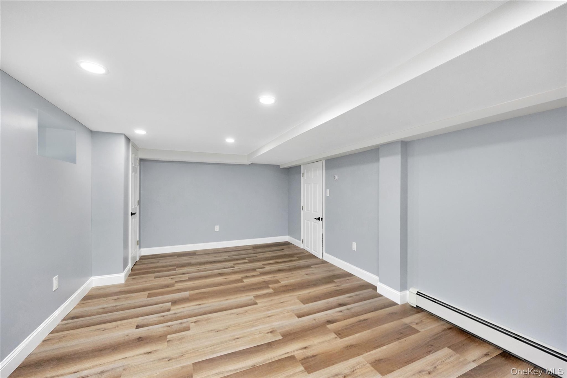 Finished basement featuring a baseboard heating unit, recessed lighting, and light wood-type flooring