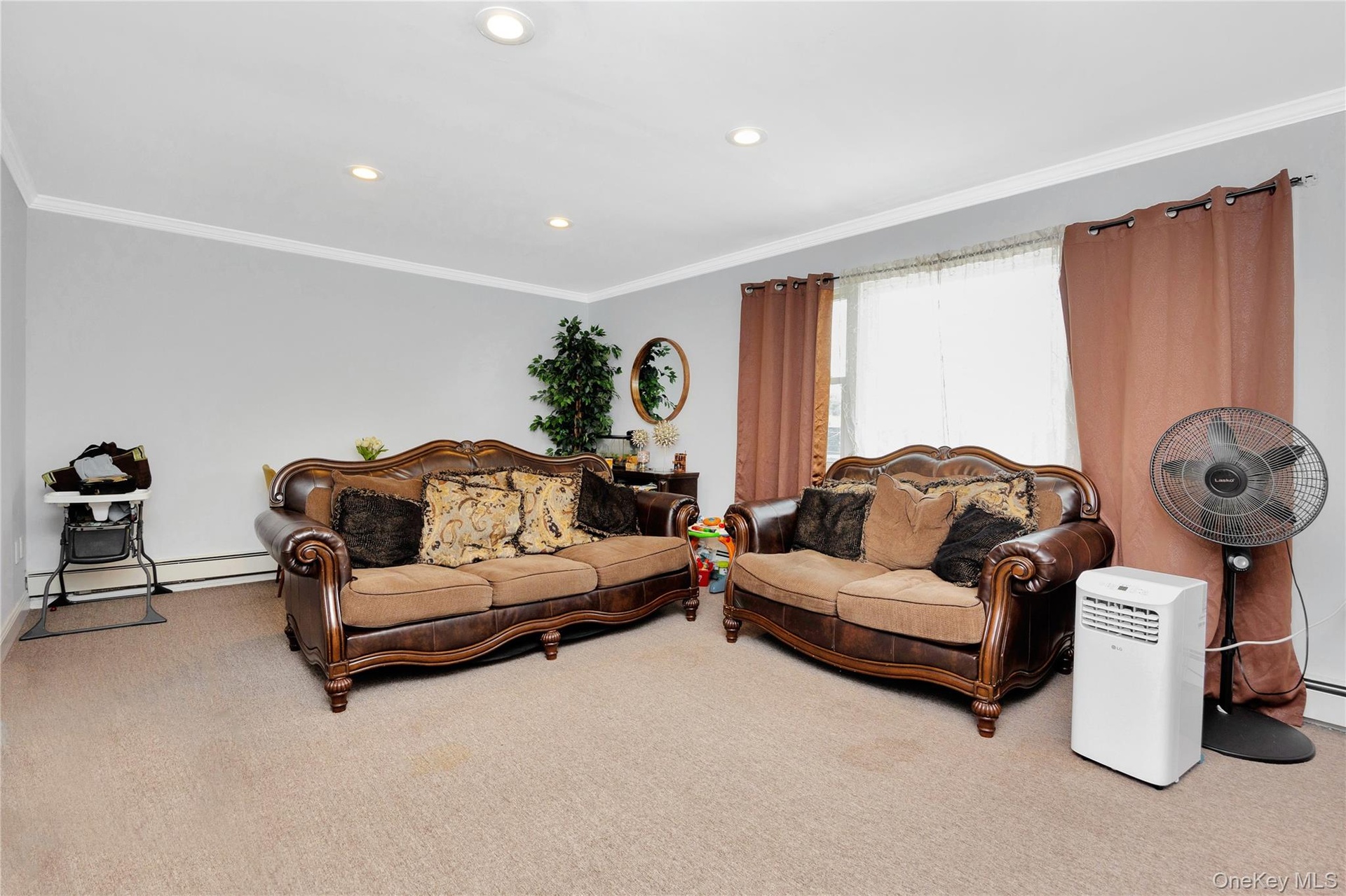 Carpeted living area with crown molding, recessed lighting, and a baseboard heating unit