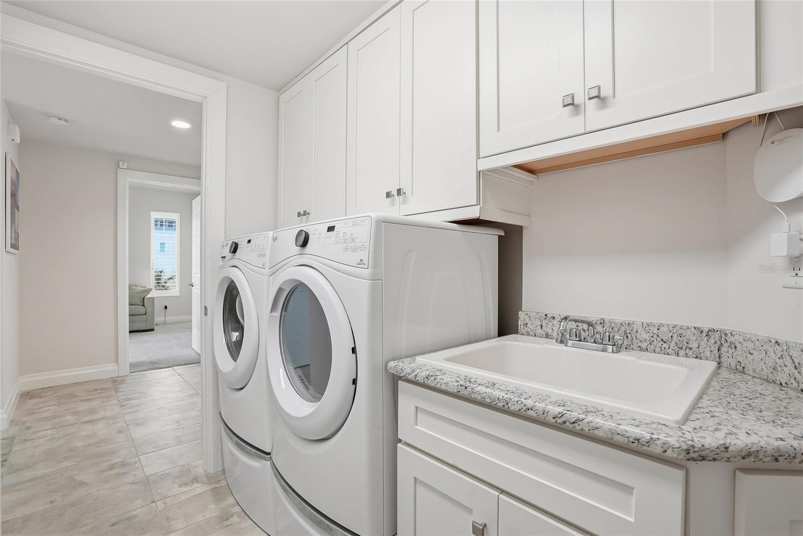 Laundry room with built-in cabinetry and utility sink.