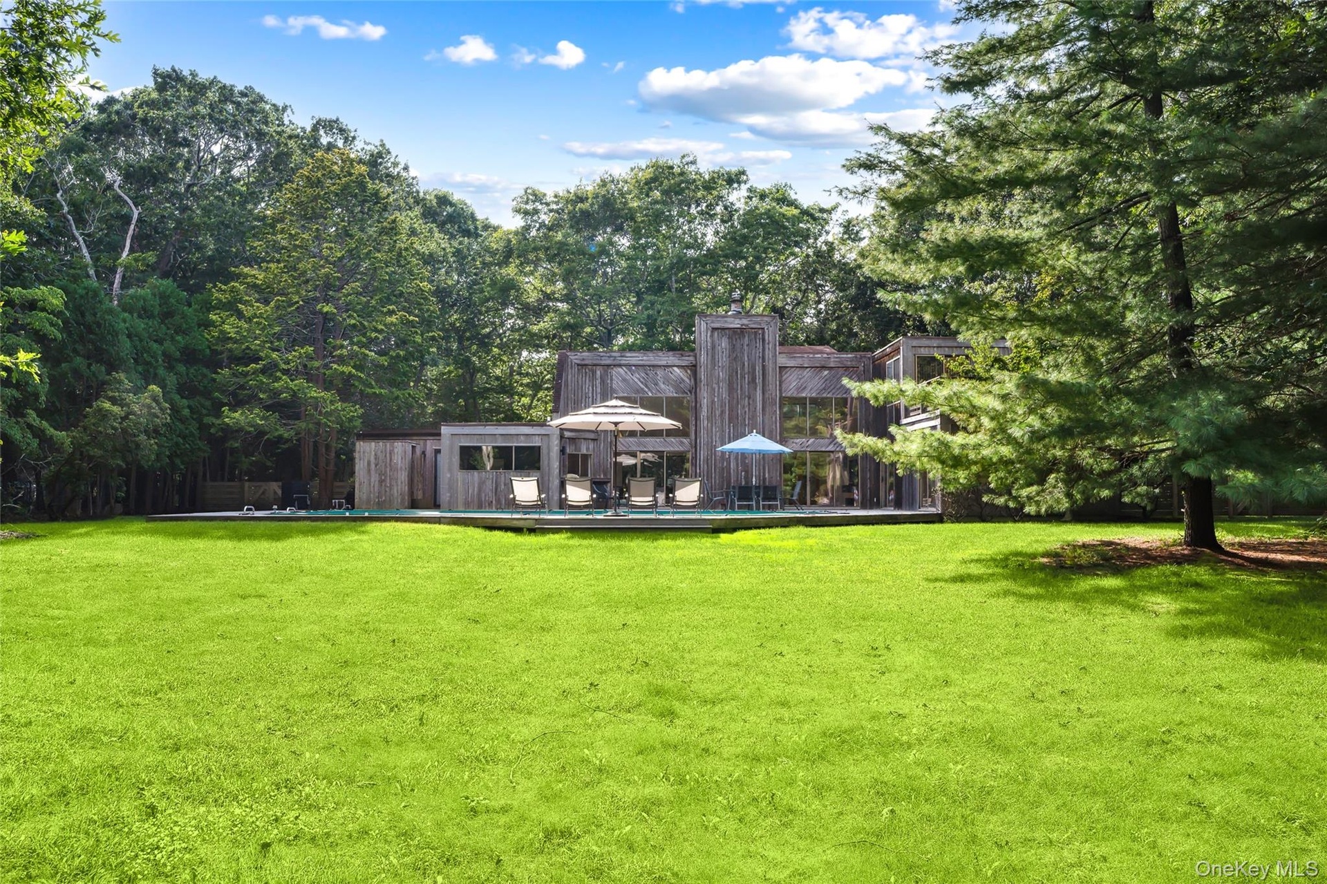 Back of property with a yard, view of wooded area, and a deck