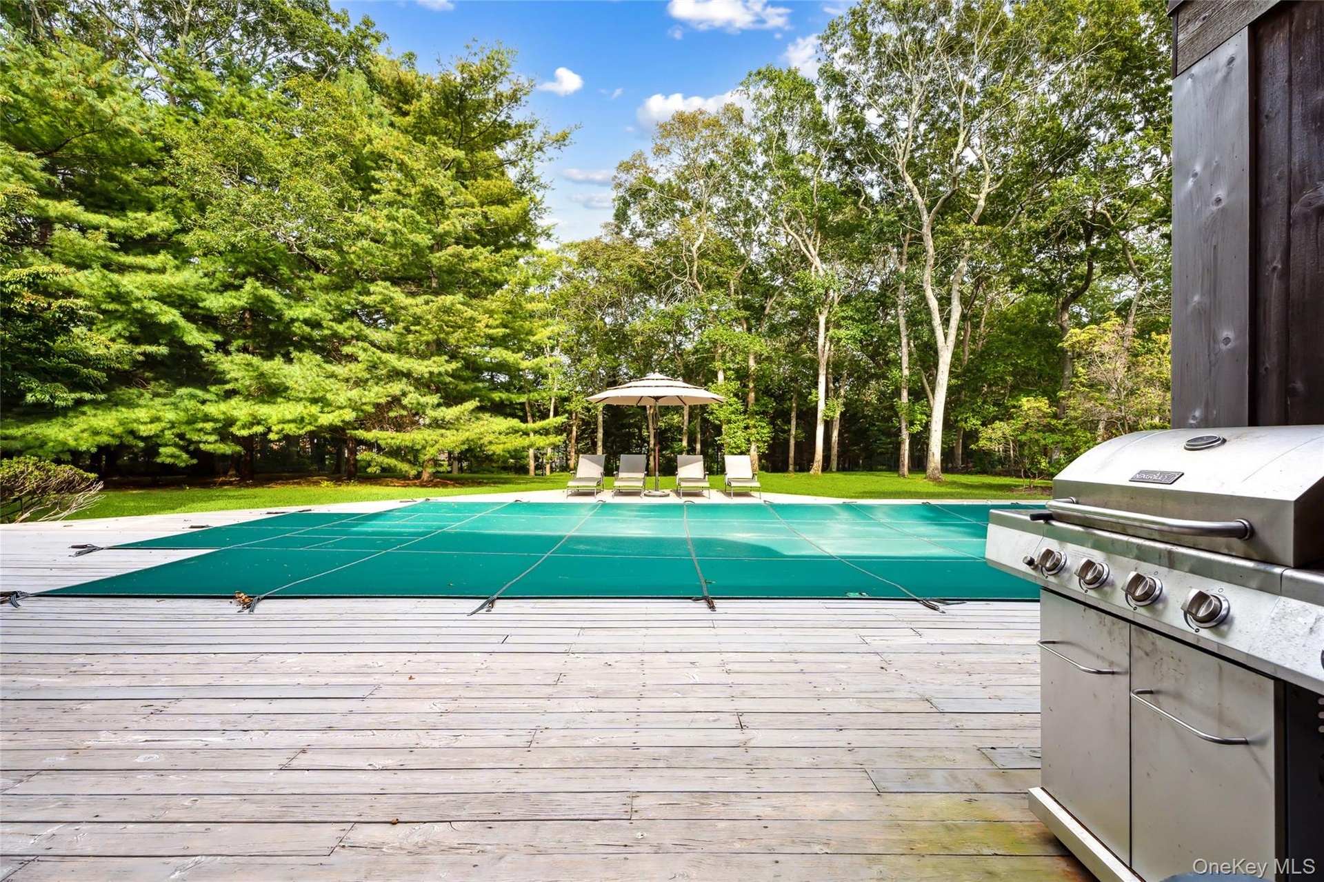 View of pool featuring a covered pool, a gazebo, view of scattered trees, and a wooden deck
