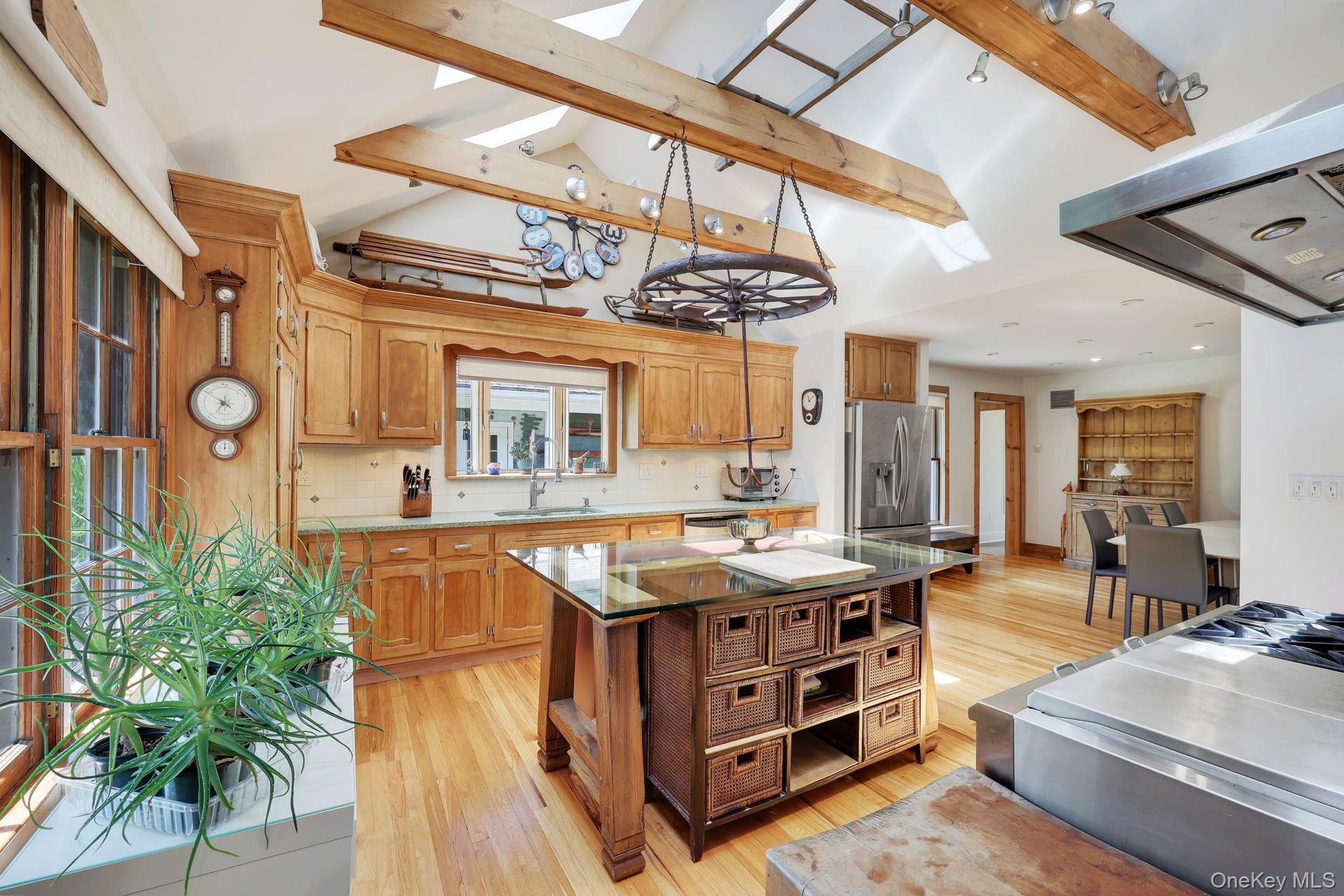 Kitchen with natural wood cabinetry, stainless steel appliances, hard wood flooring, wooden beams and skylights.