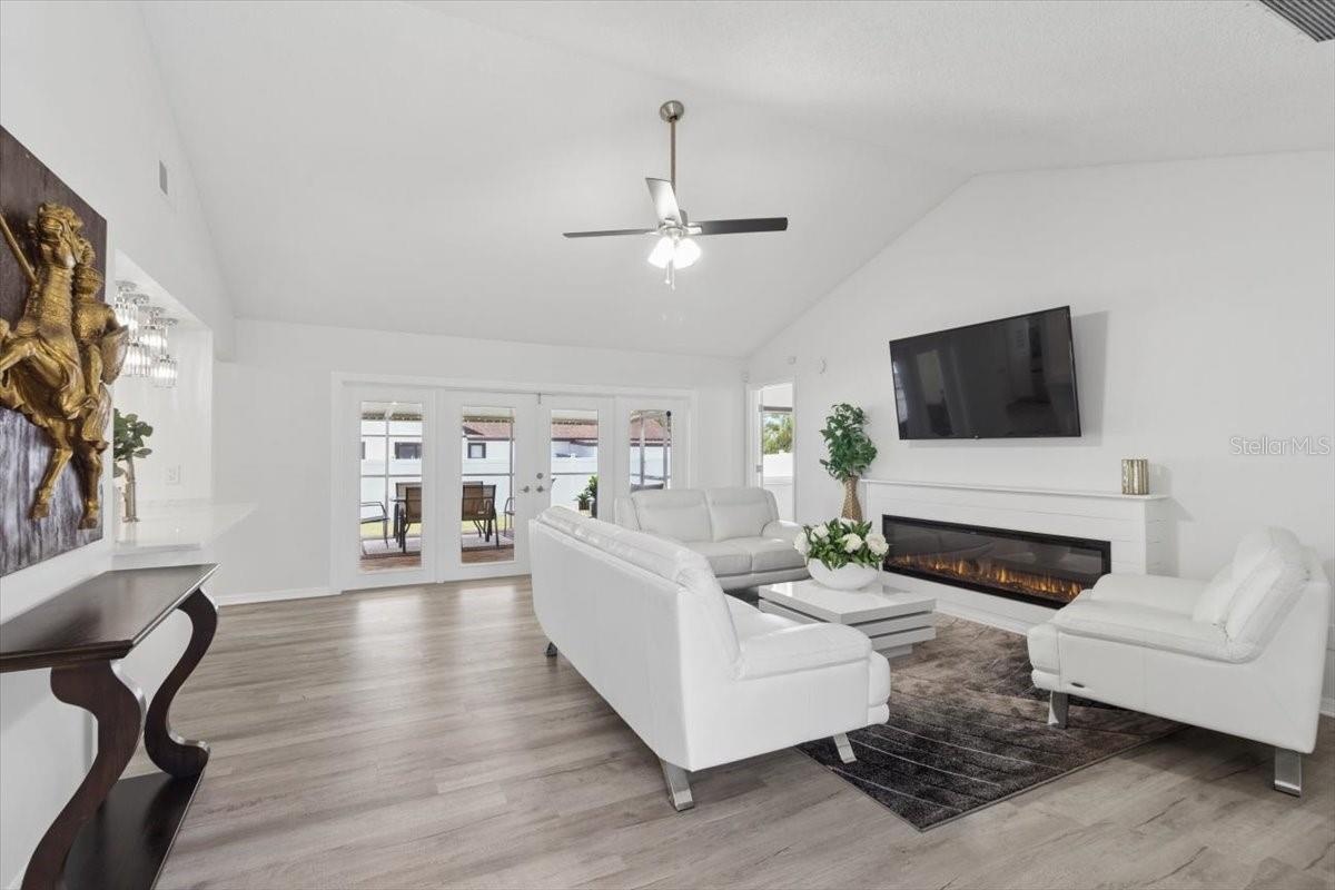 Designed for both comfort and entertaining, the spacious living room showcases elegant French doors leading to the backyard and a stylish faux firepla