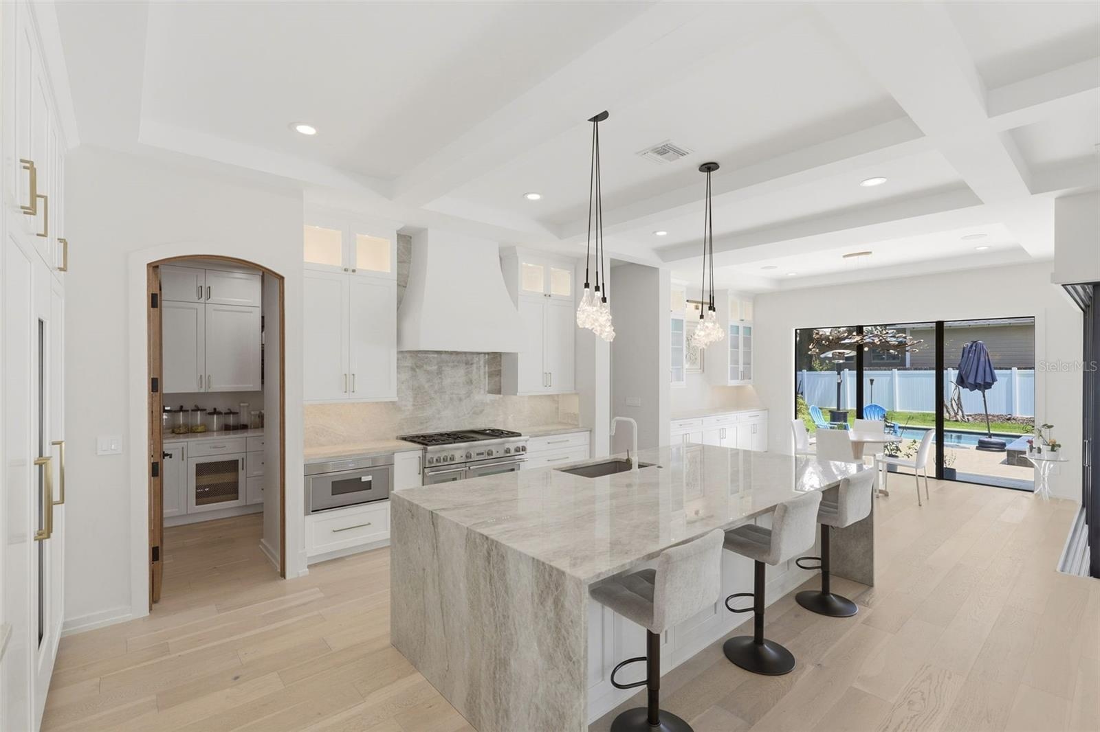 Kitchen features crystallized quartzite counters, oversized waterfall island & walk-in panty