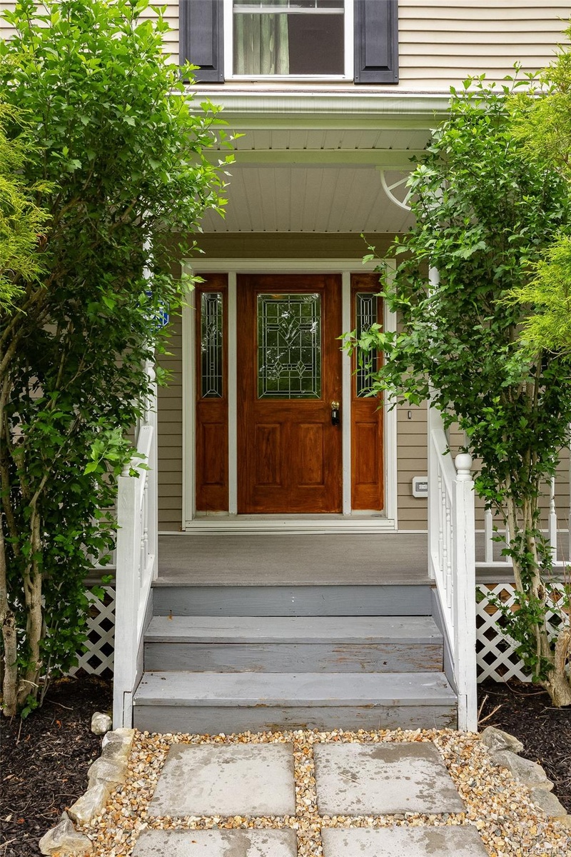 Inviting entryway featuring a rich wood-finish front door with leaded glass, flanked by coordinating sidelights