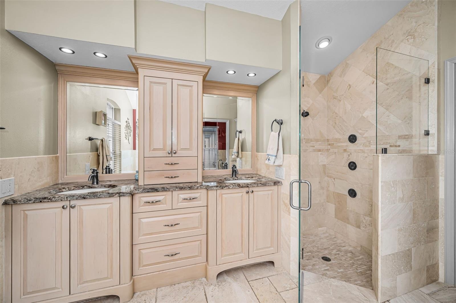 Primary bathroom with dual vanities and glass enclosed shower