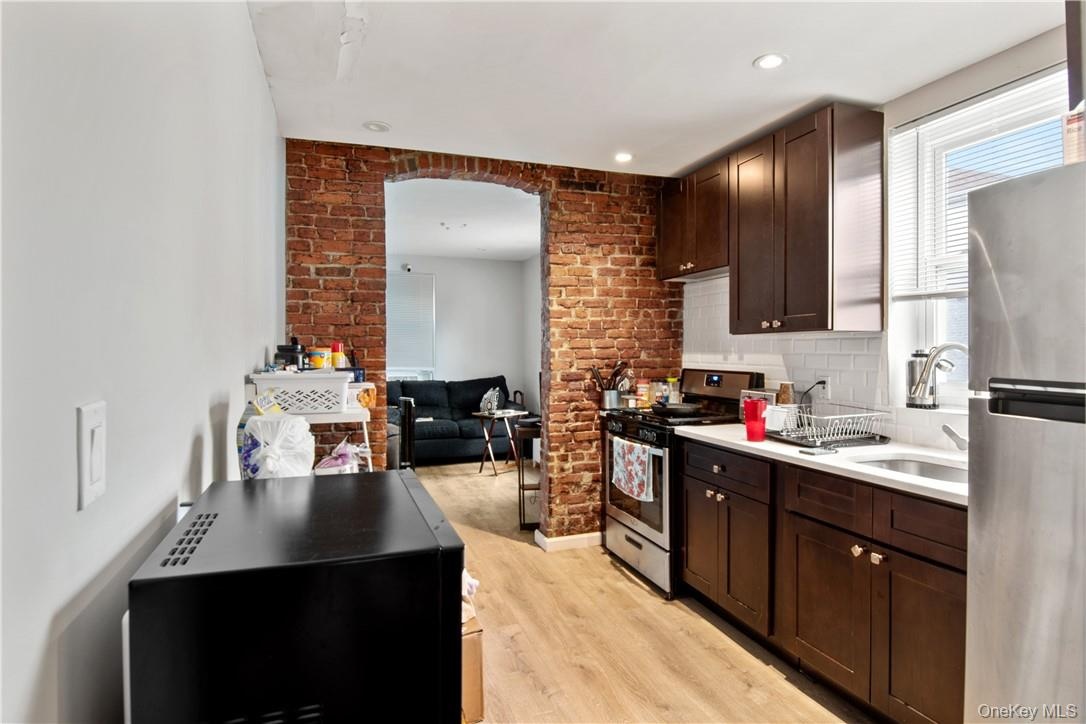 Kitchen featuring wood-finish flooring and an exposed brick accent wall