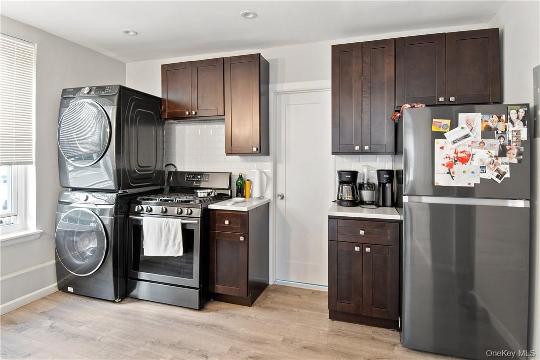 Compact kitchen featuring a stainless steel gas range, dark wood-finish cabinetry, light-colored countertops, and wood-finish flooring