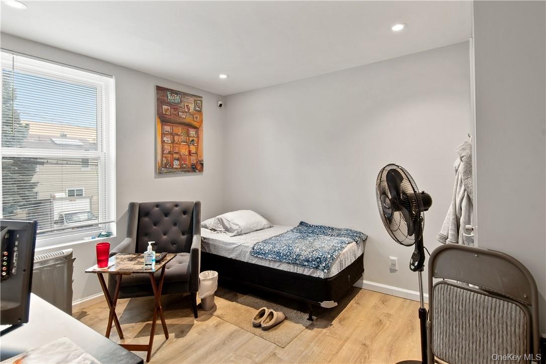 Bedroom featuring light wood-finish flooring, recessed lighting, and a window with blinds