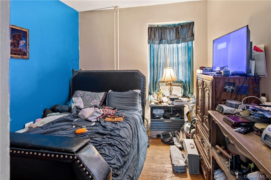 Room featuring wood-finish flooring, two-tone wall paint, and a window with curtains