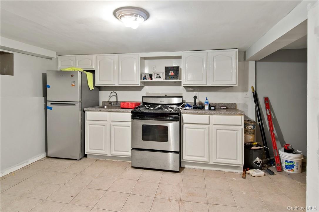 Kitchenette featuring white cabinetry, stainless steel refrigerator, stainless steel range, and tile flooring