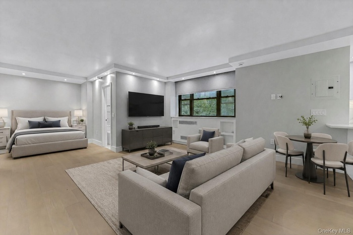 Open-concept living space with light wood-finish flooring, recessed lighting, and a large window