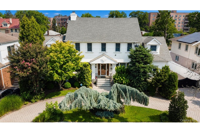 White Colonial-style residence featuring a gray shingle roof and multiple dormer windows