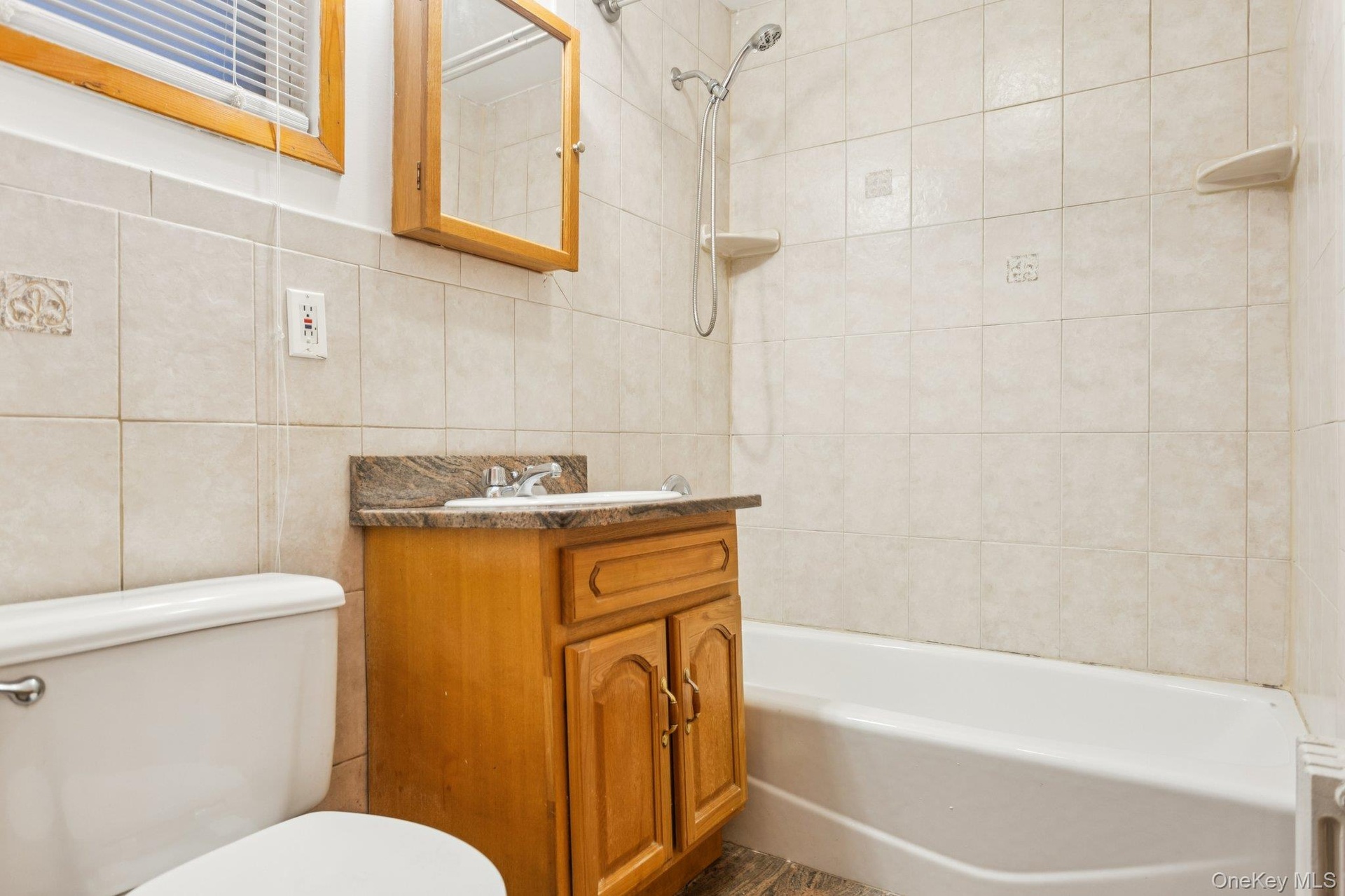 Bathroom featuring tile walls, vanity,  shower combination, and decorative backsplash