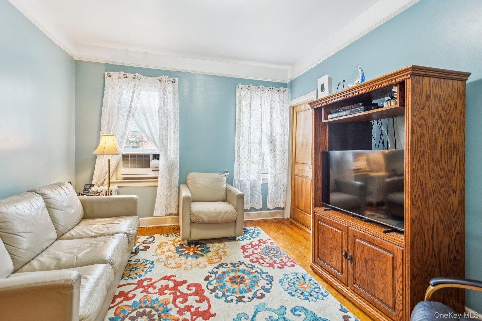 Living room featuring light wood-style flooring, crown molding, and cooling unit