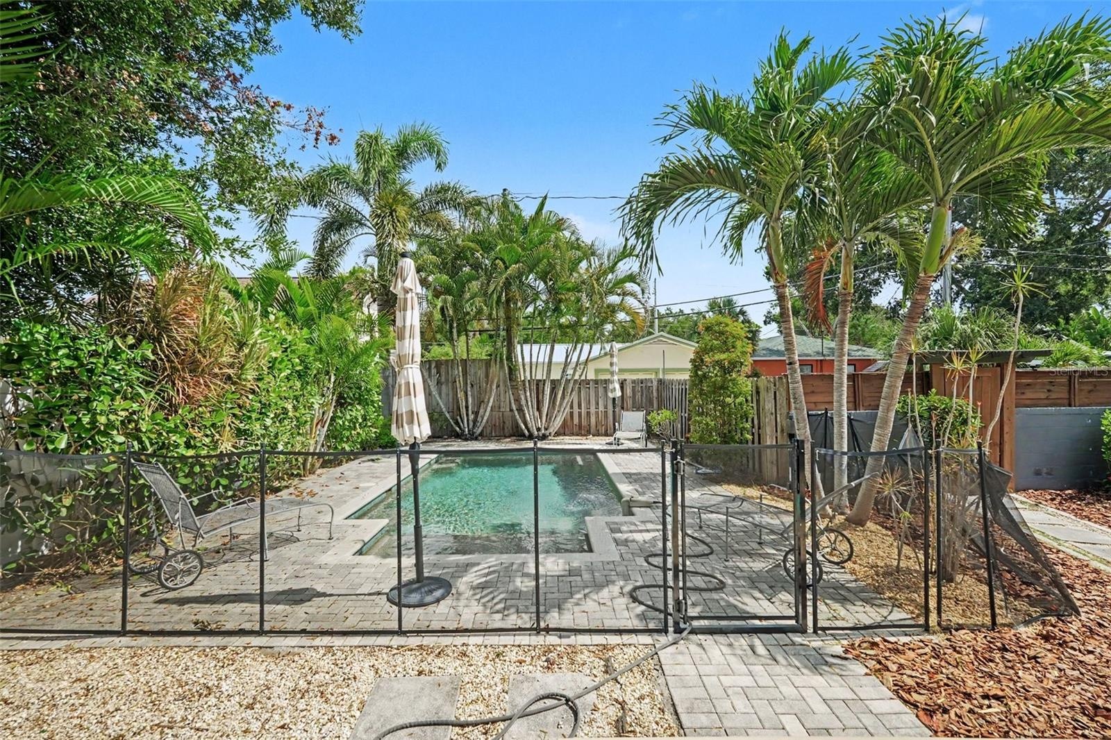 The private backyard pool is surrounded by mature tropical landscaping, creating a lush setting for relaxing and entertaining.