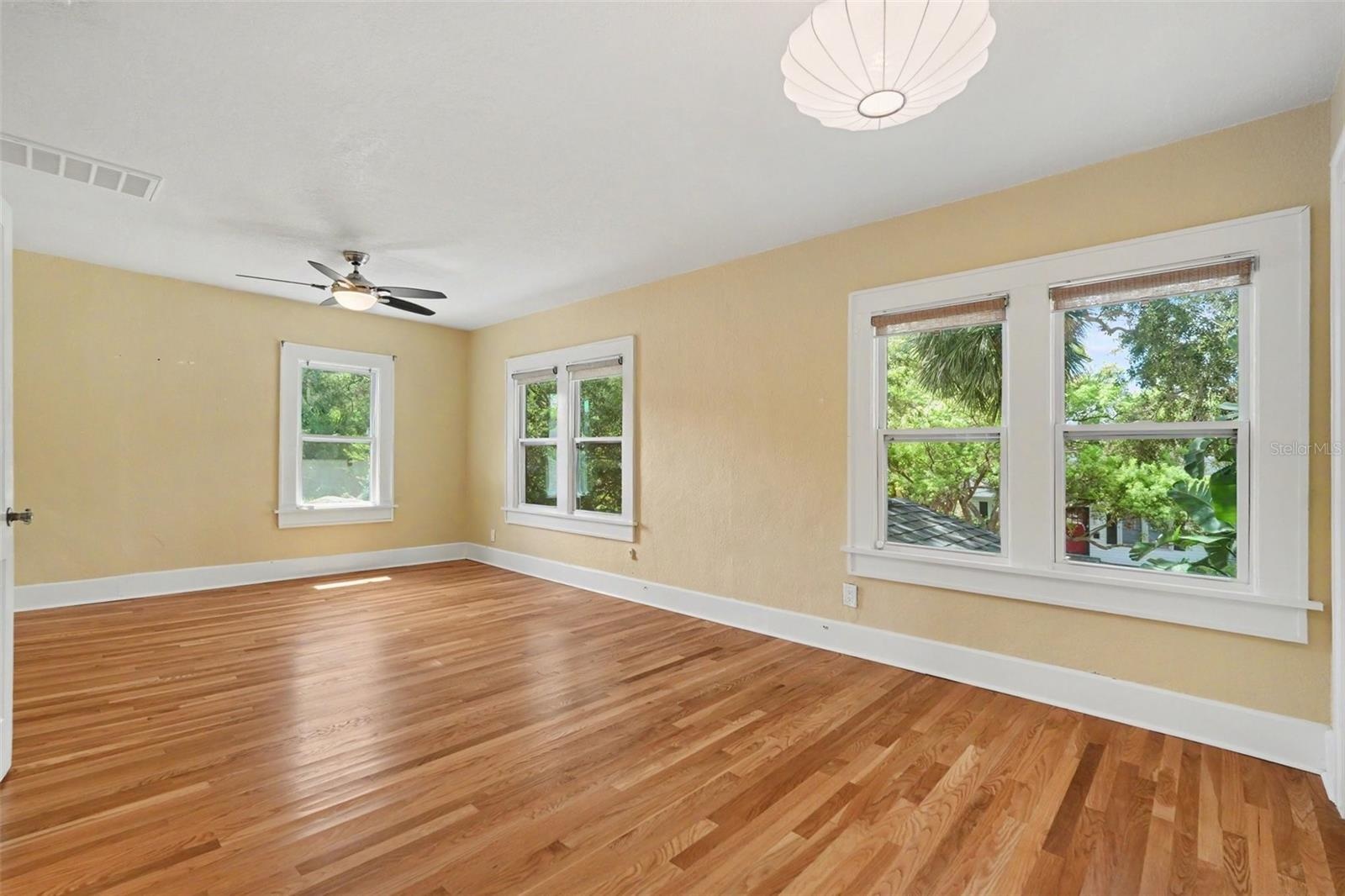 Multiple windows frame leafy neighborhood views, giving the primary bedroom a bright and peaceful feel.