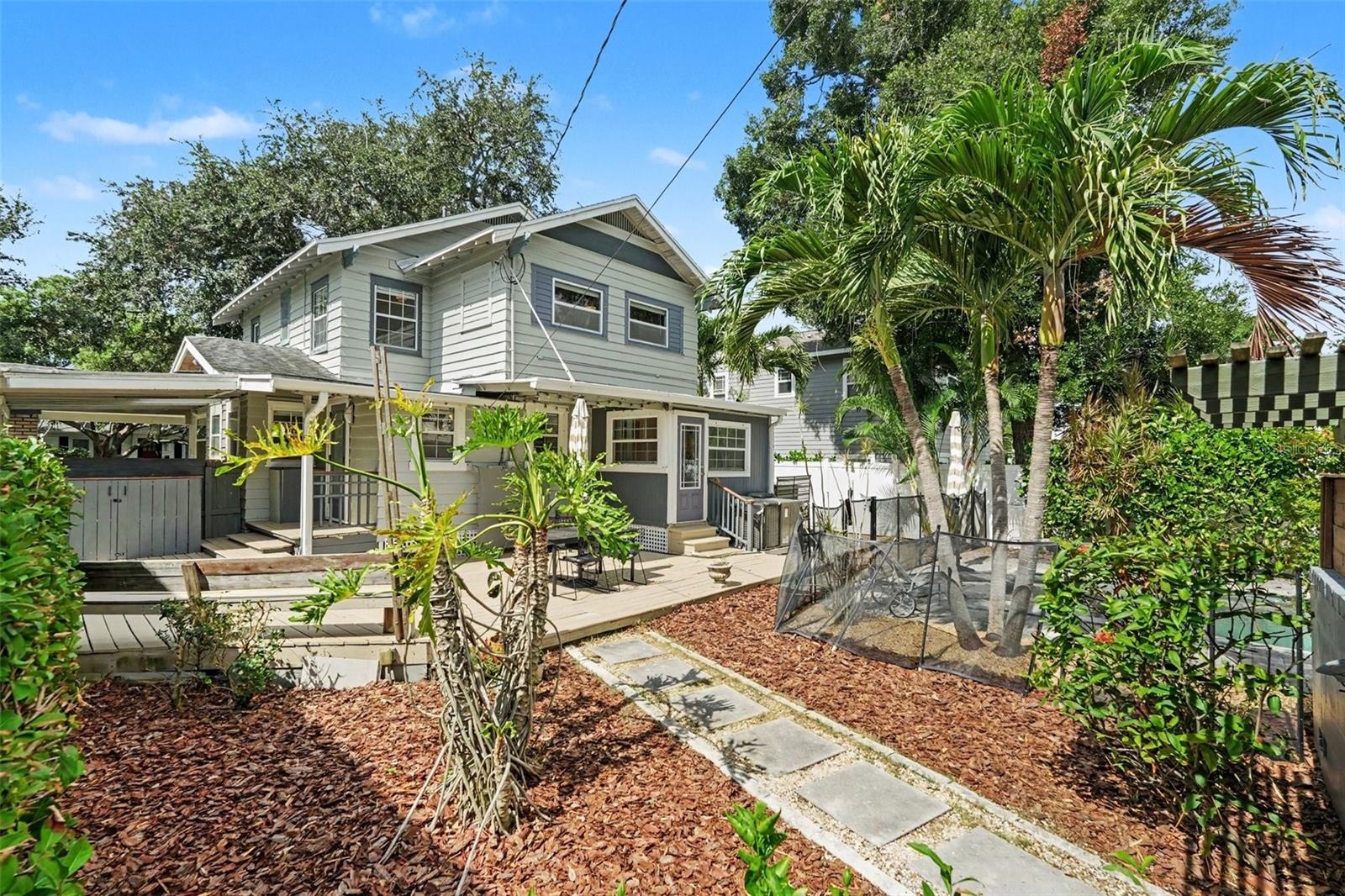 The backyard offers more than just a pool, with tropical landscaping, garden space, and multiple outdoor areas to enjoy.