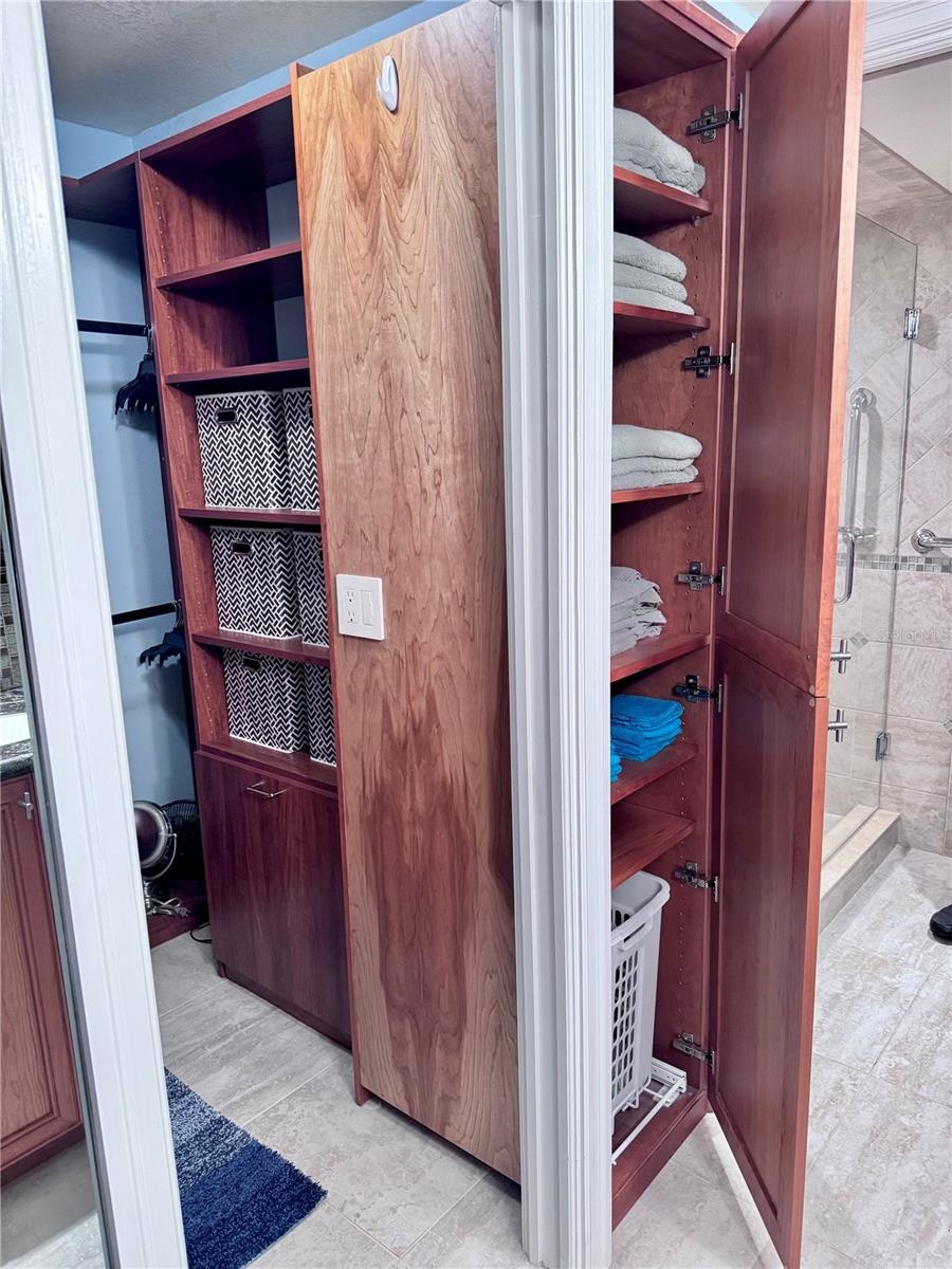 Built in clothes hamper adjacent to primary walk in closet