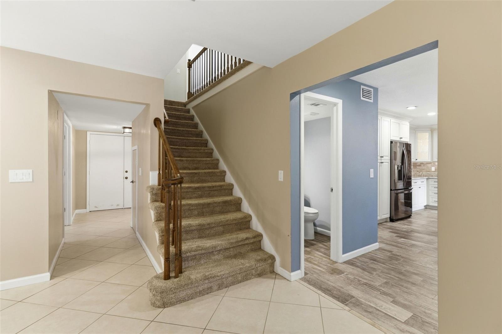 View of entry doors, half bath, kitchen and stairs