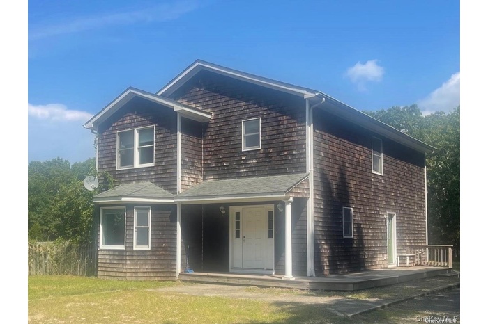 Two-story residence featuring wood shingle siding and a prominent covered front entry with columns