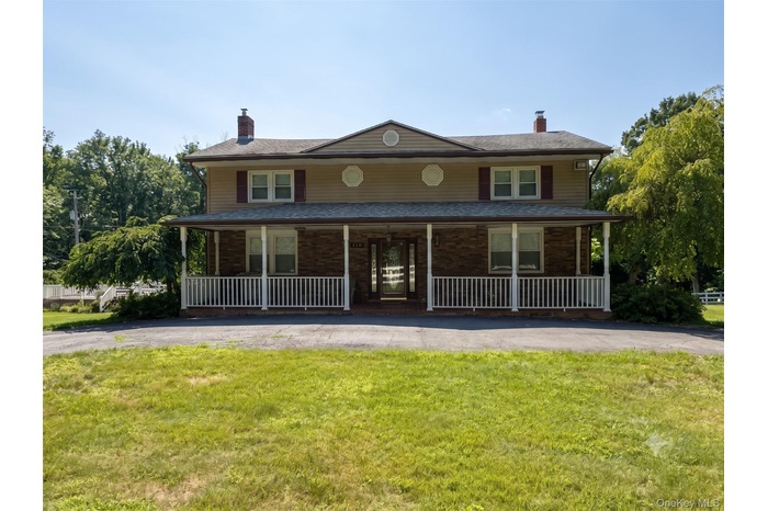 Two-story residence featuring a full-width front porch with white railing, brick and siding exterior, and a central double-door entry