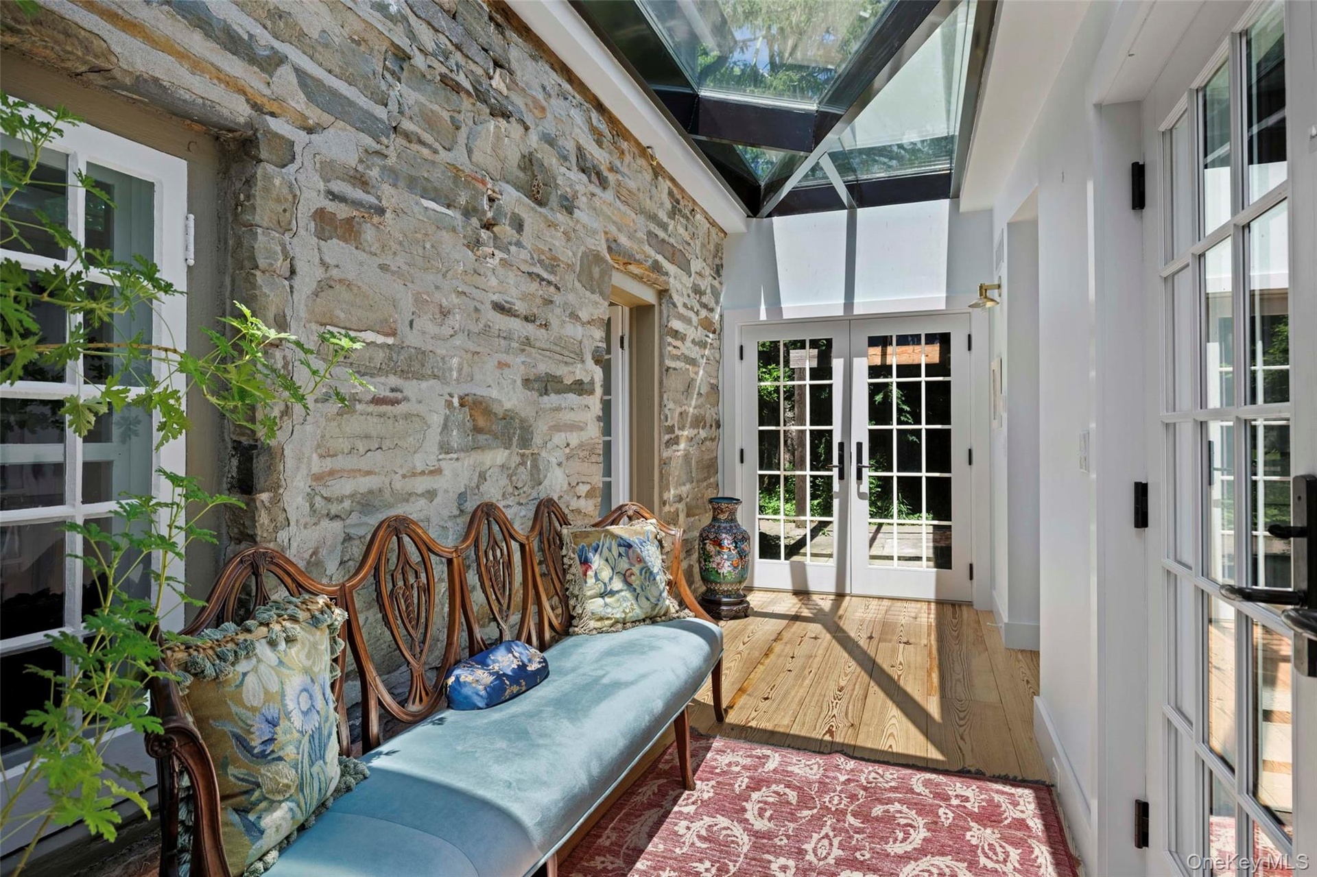 This thoughtfully designed glass-enclosed passage preserves the original stone wall while dramatic skylights flood the space with natural light, creat