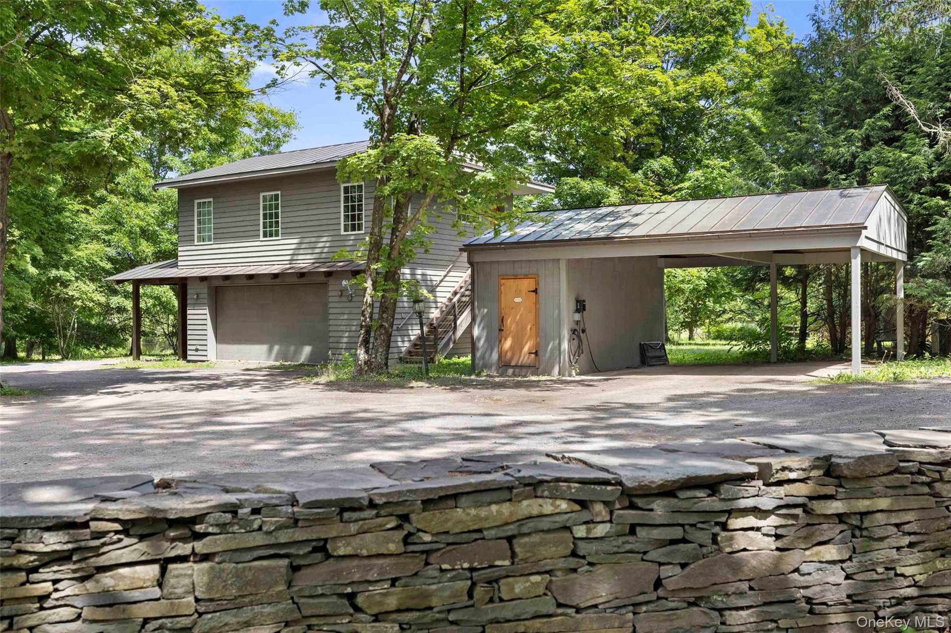 Detached garage with one-bedroom apartment above, covered carport, and EV charging station