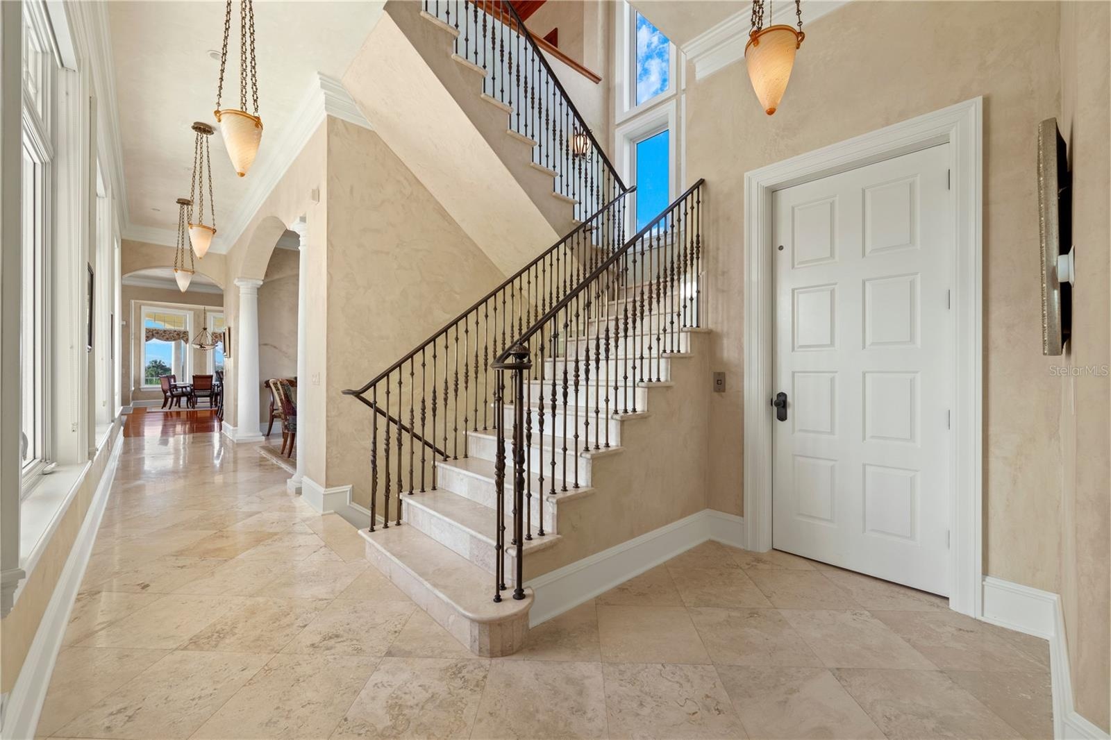 A striking architectural centerpiece, the sweeping staircase draws the eye upward while artisan ironwork and soft natural light create a memorable fir