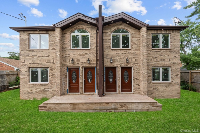 Two-story brick facade featuring multiple entry doors with decorative glass inserts, arched windows on the second level, rectangular windows on both l