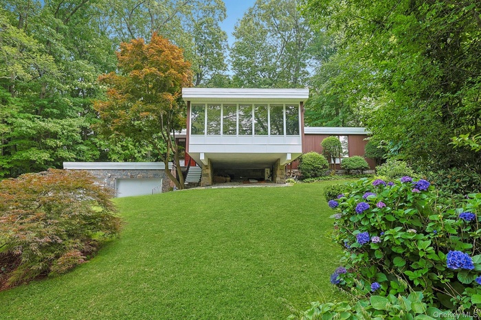 A striking Mid-Century Modern residence nestled among mature trees, showcasing clean architectural lines, dramatic walls of glass, and exceptional cur