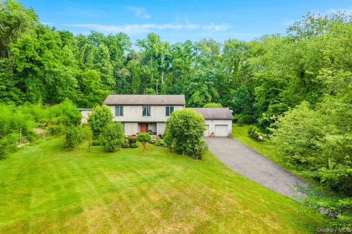 Two-story residence with a two-car garage, long asphalt driveway, and expansive lawn