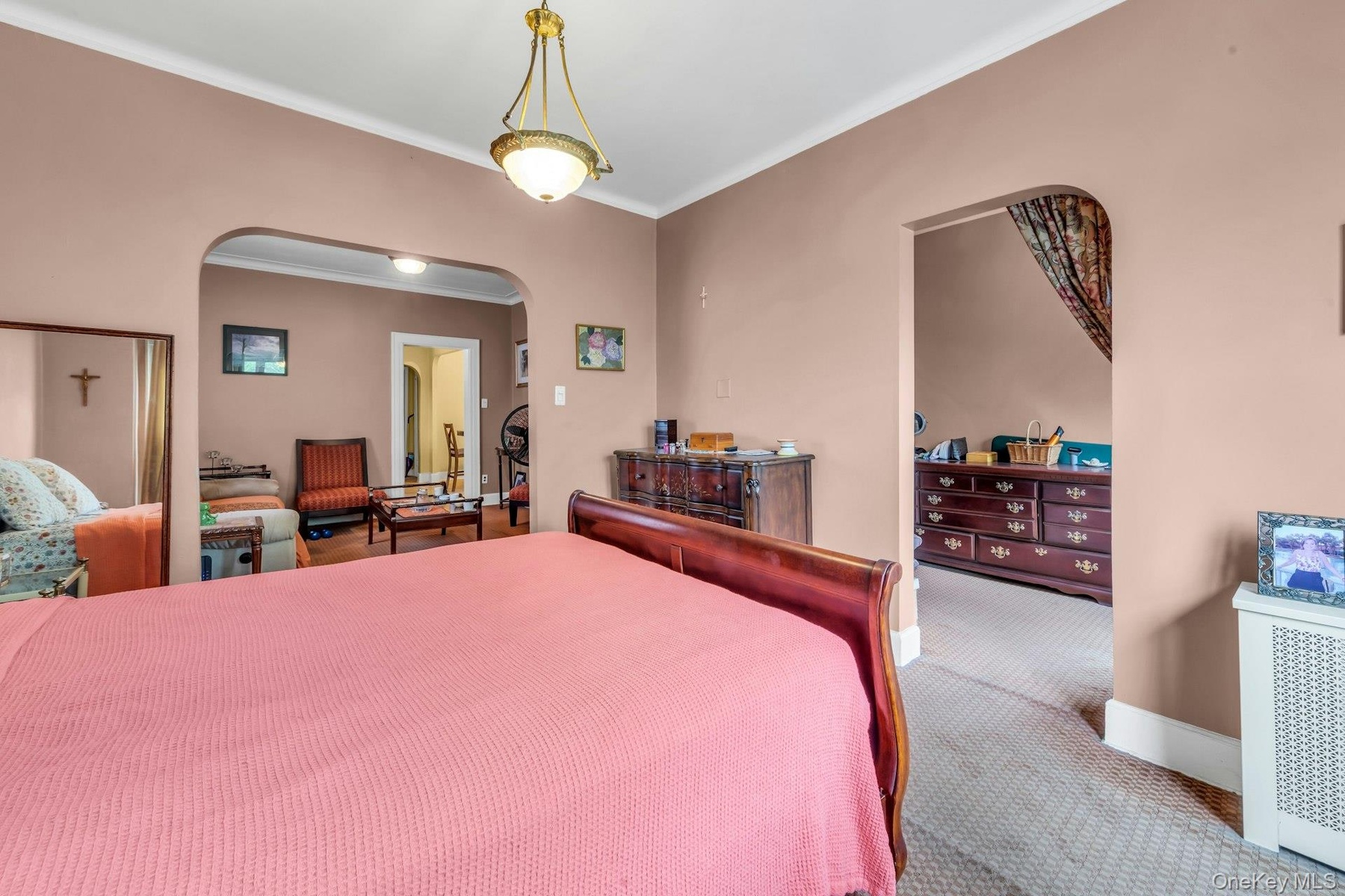 Second floor apartment bedroom with archway into living room and bonus room.