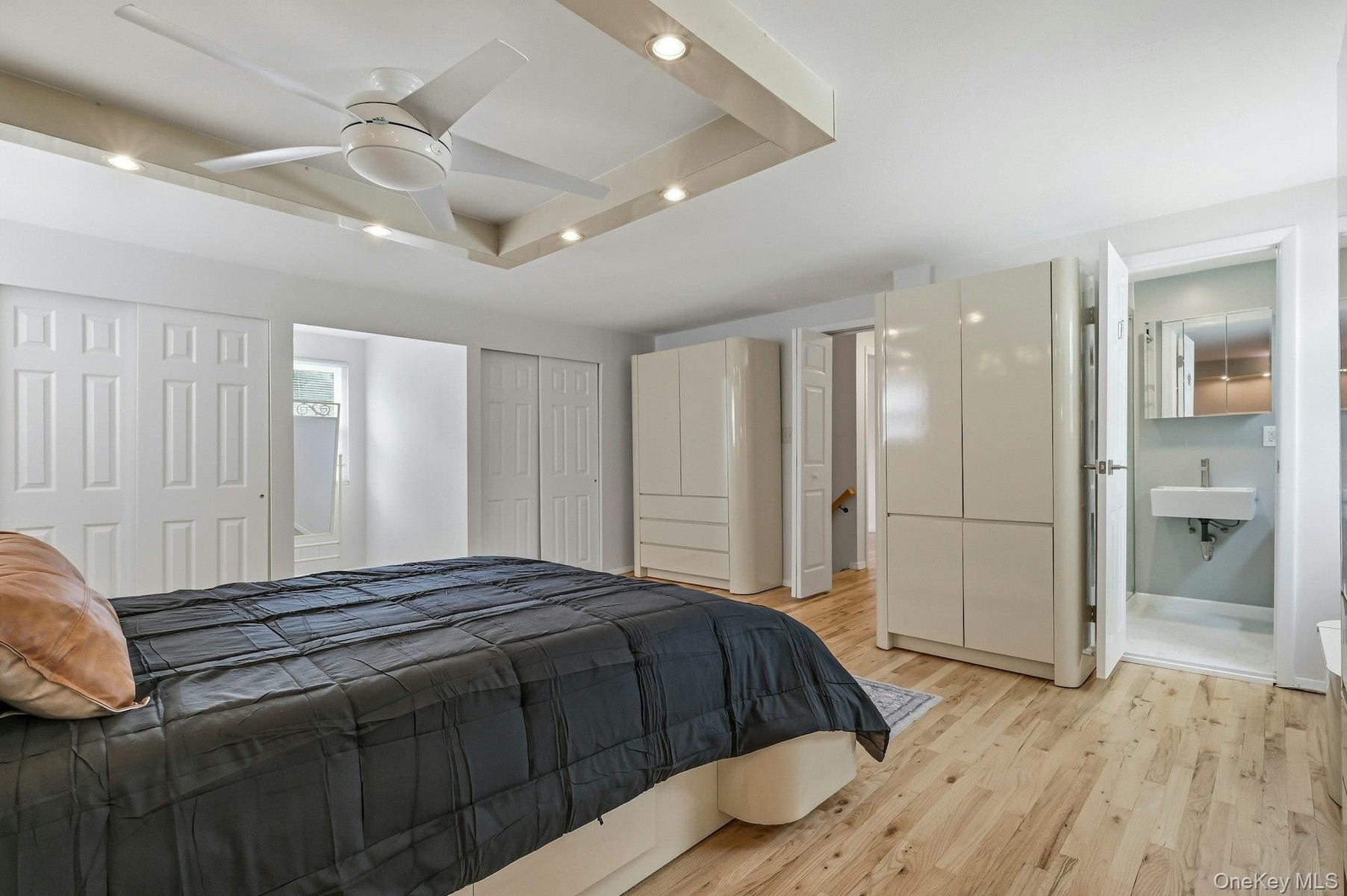 Recessed ceiling with integrated lighting, a ceiling fan, and wood-finish flooring